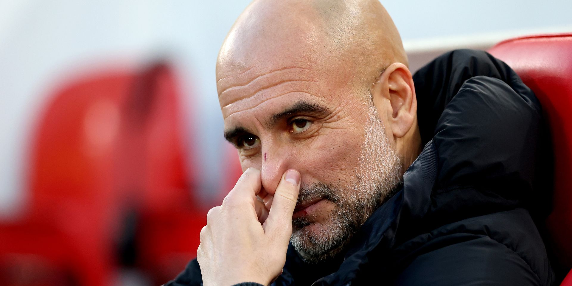 Pep Guardiola sits on the bench at Anfield