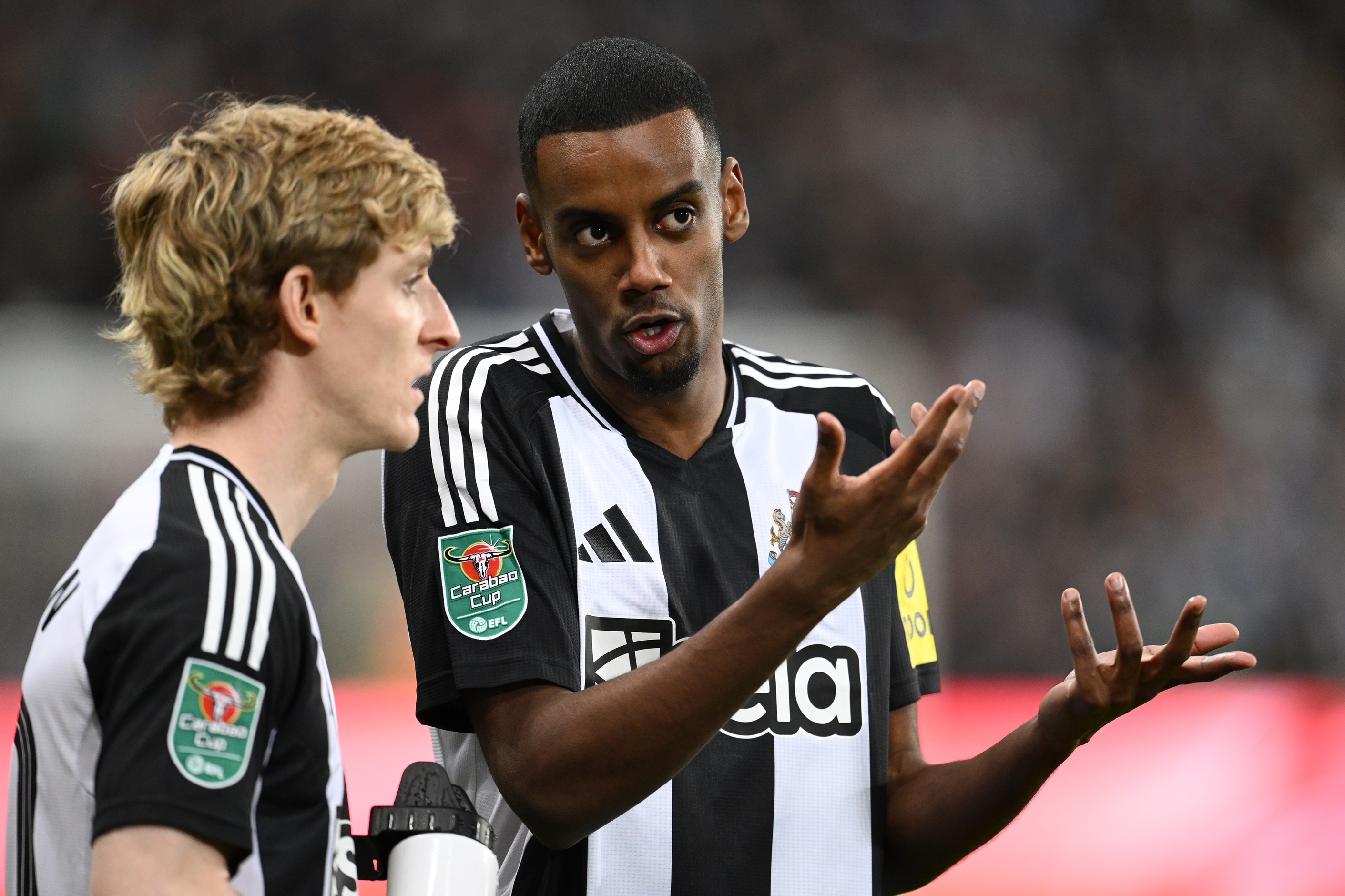 Alexander Isak in discussion with Anthony Gordon during Carabao Cup game.