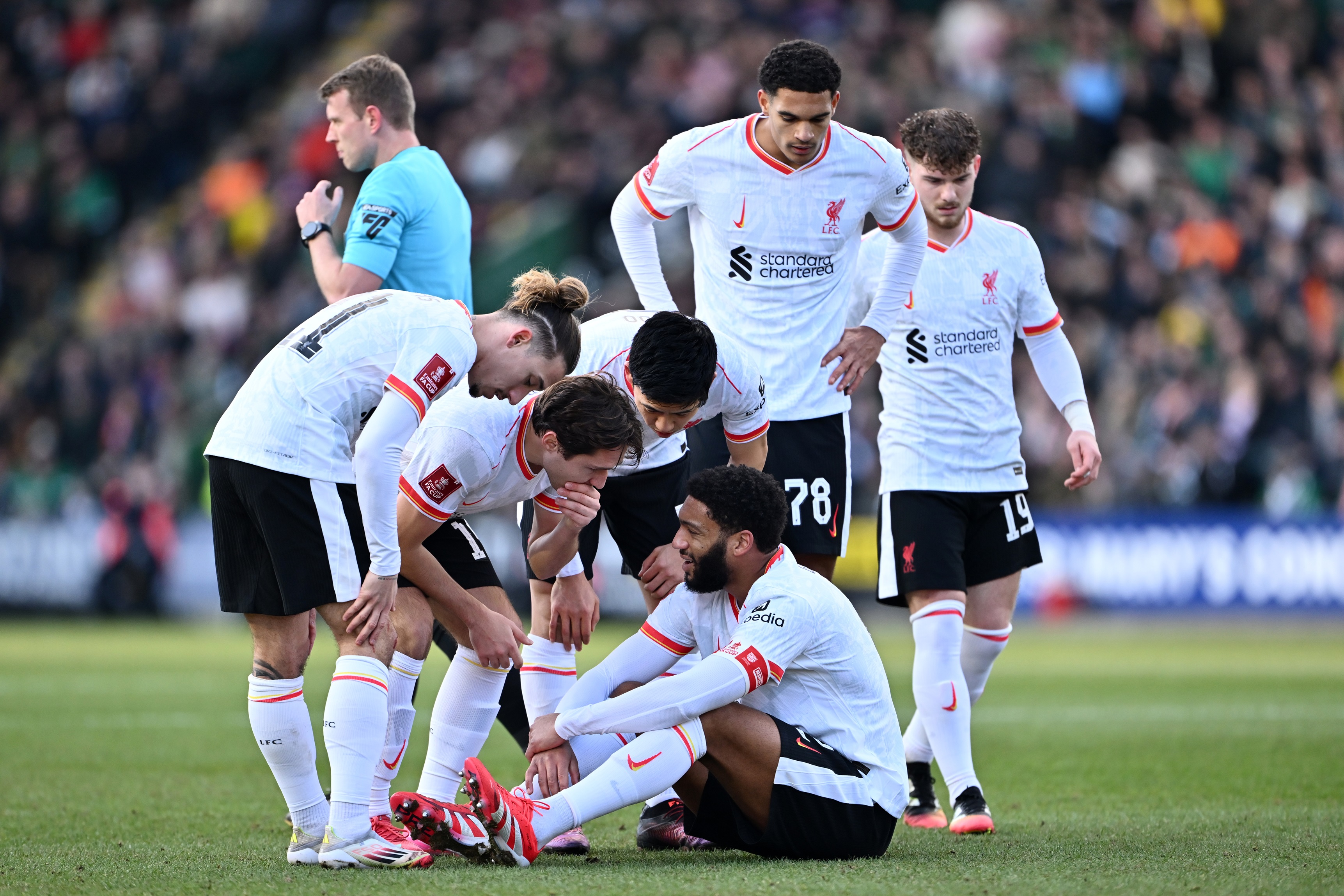 Liverpool players comfort Joe Gomez as he lies down on the ground.
