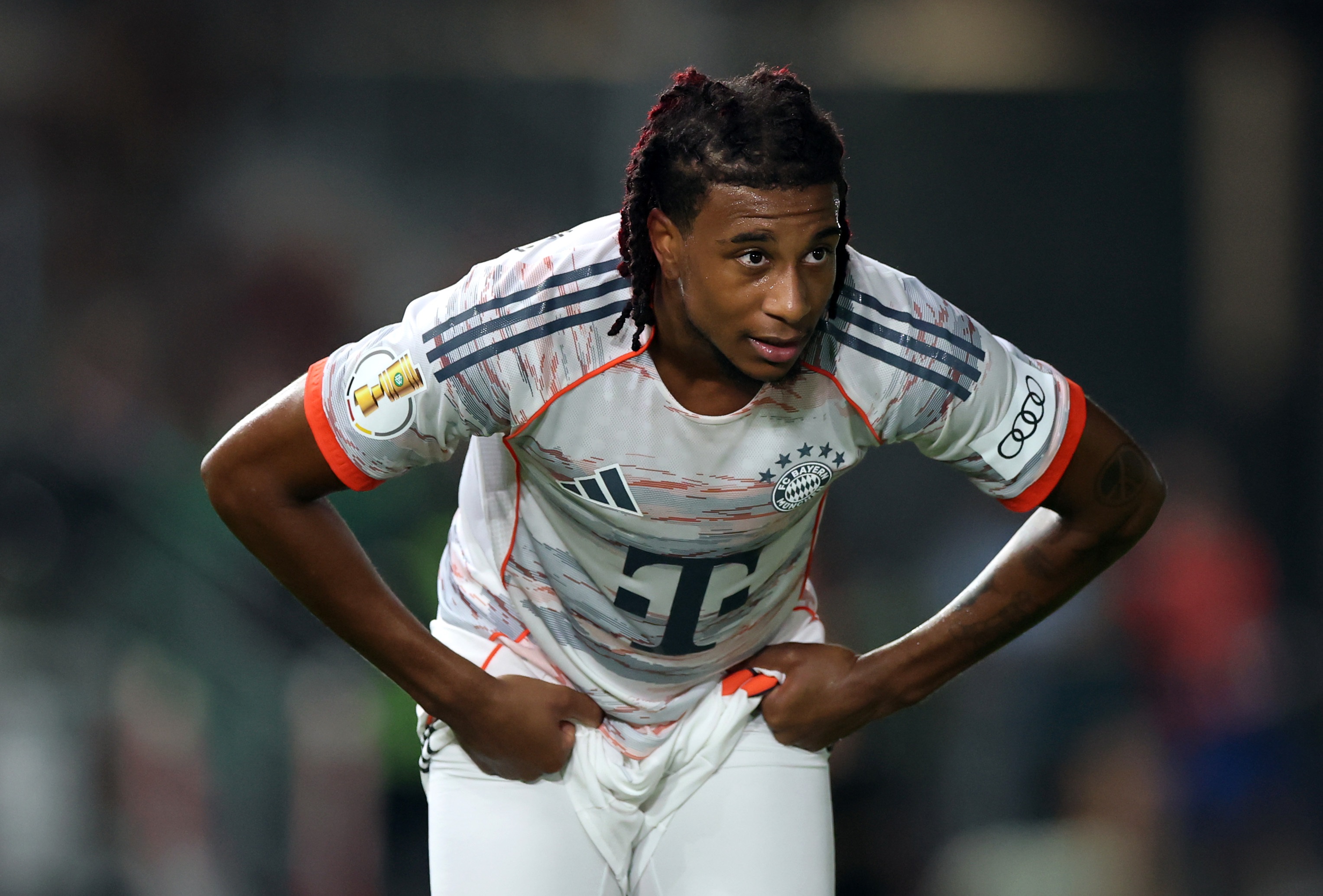 Michael Olise bends over and puts his hands on his waist during Bayern Munich game.