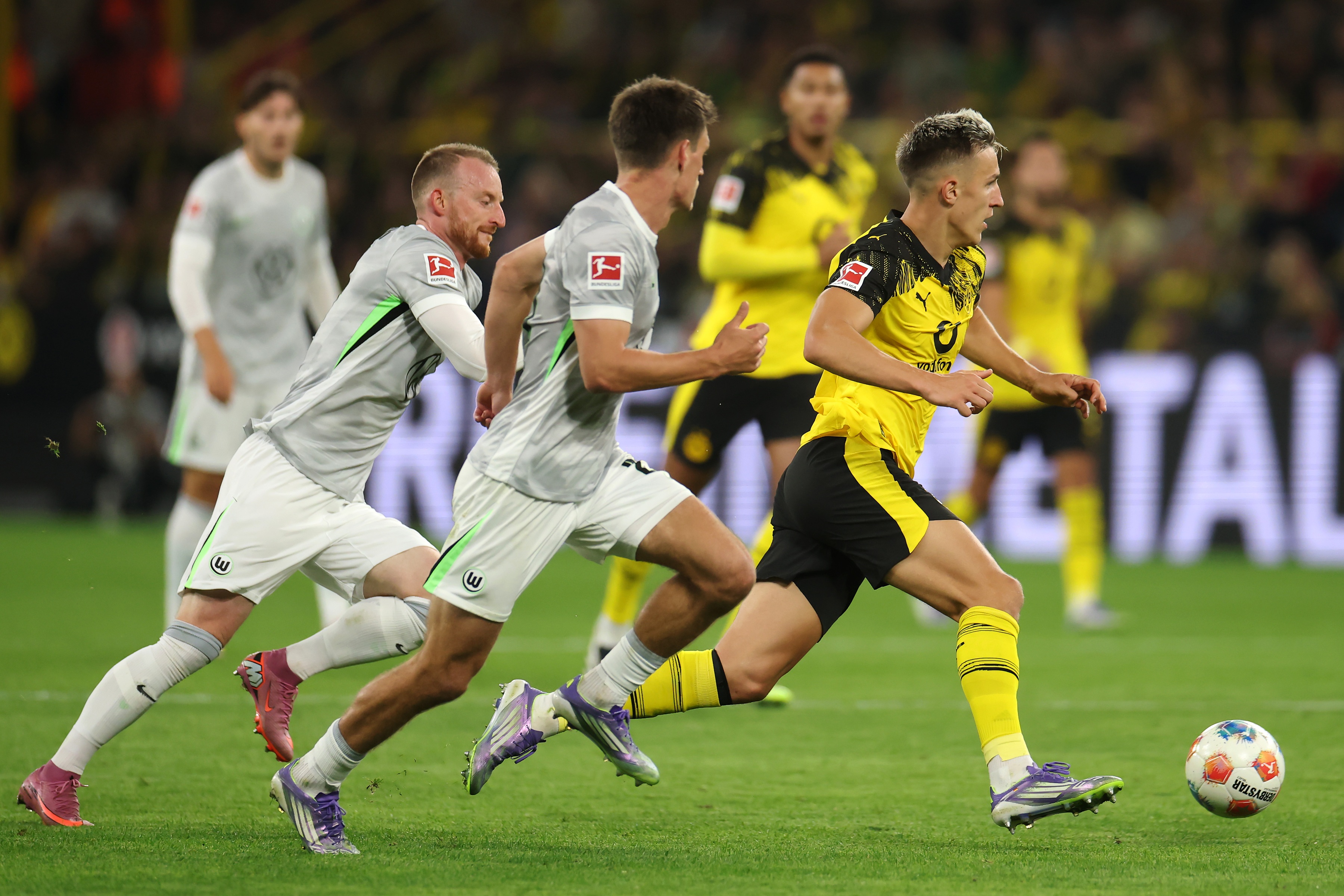 Nico Schlotterbeck dribbles away from chasing Wolfsburg players.