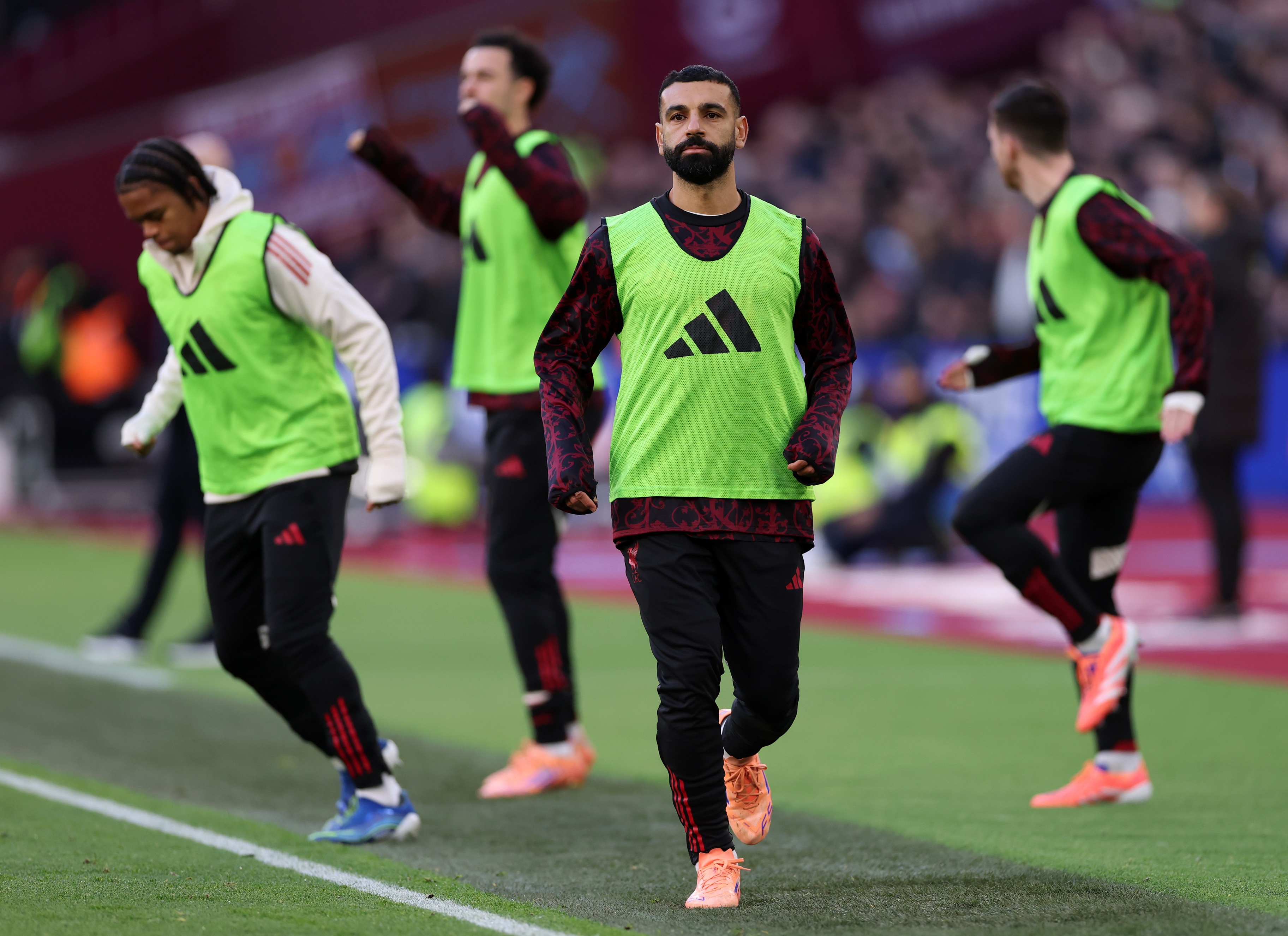 Mo Salah warms up on the touchline with fellow Liverpool substitutes.