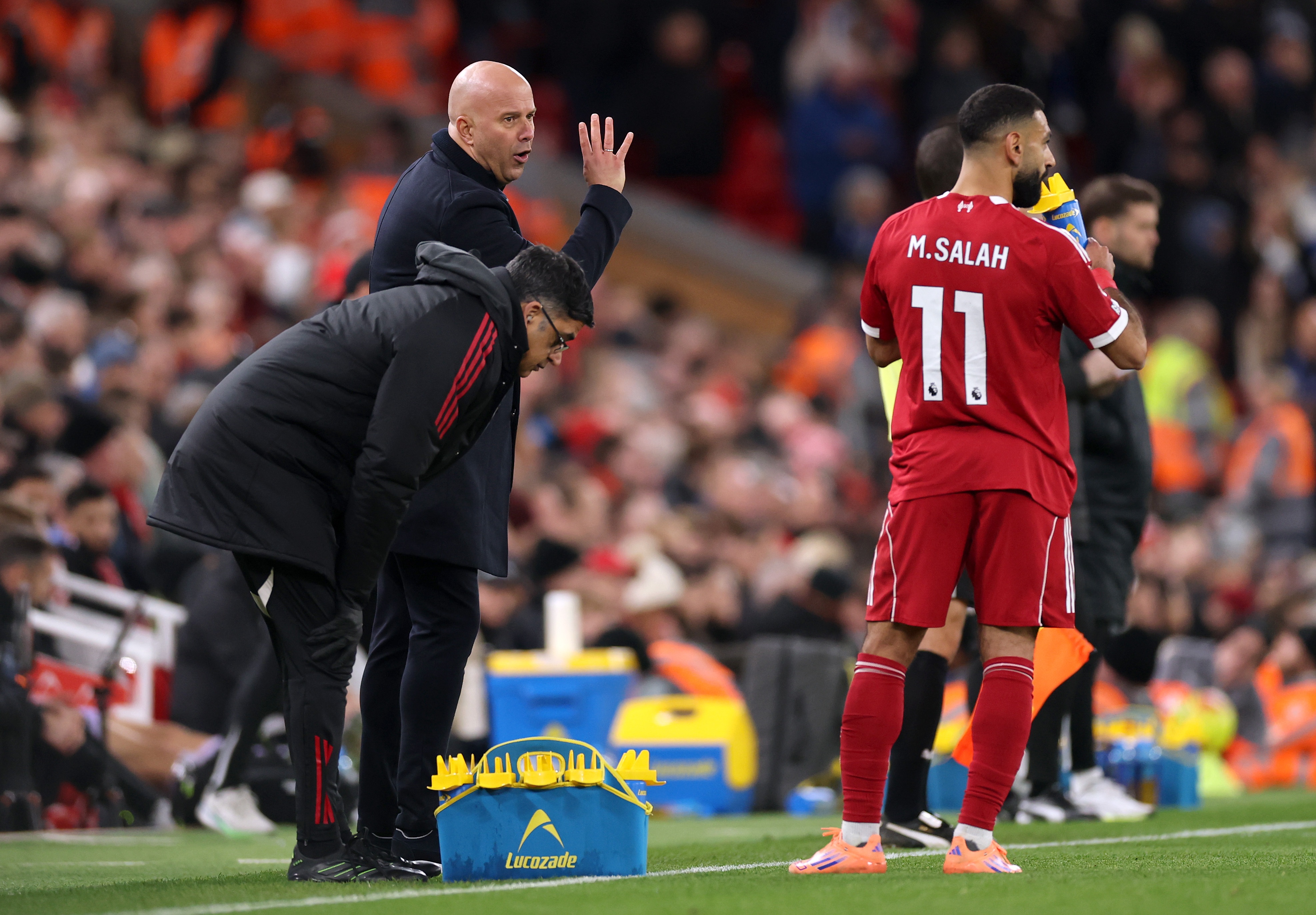 Mo Salah takes in liquids as Arne Slot gestures on the touchline.