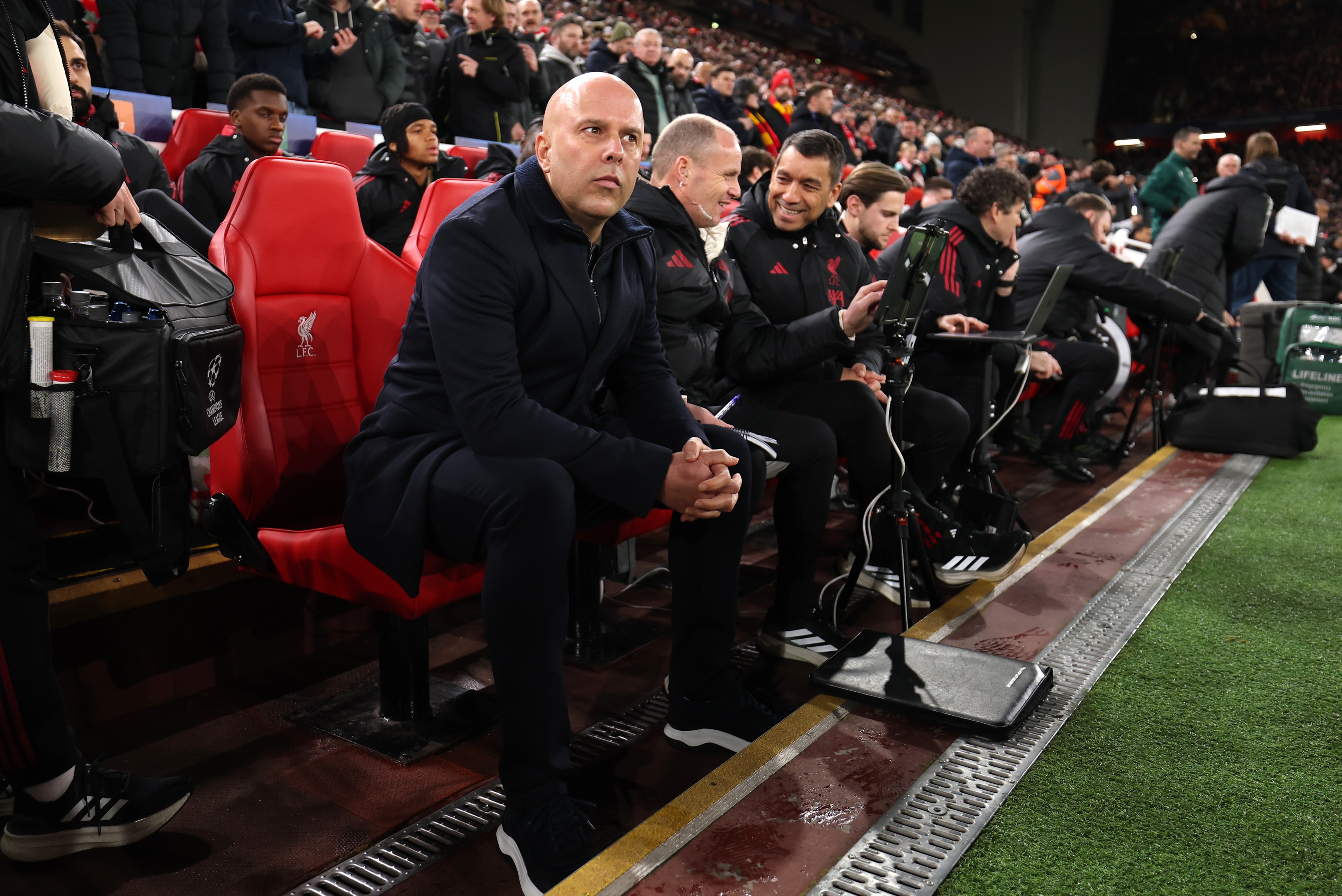 Arne Slot sits on the Liverpool bench ahead of a Champions League game.