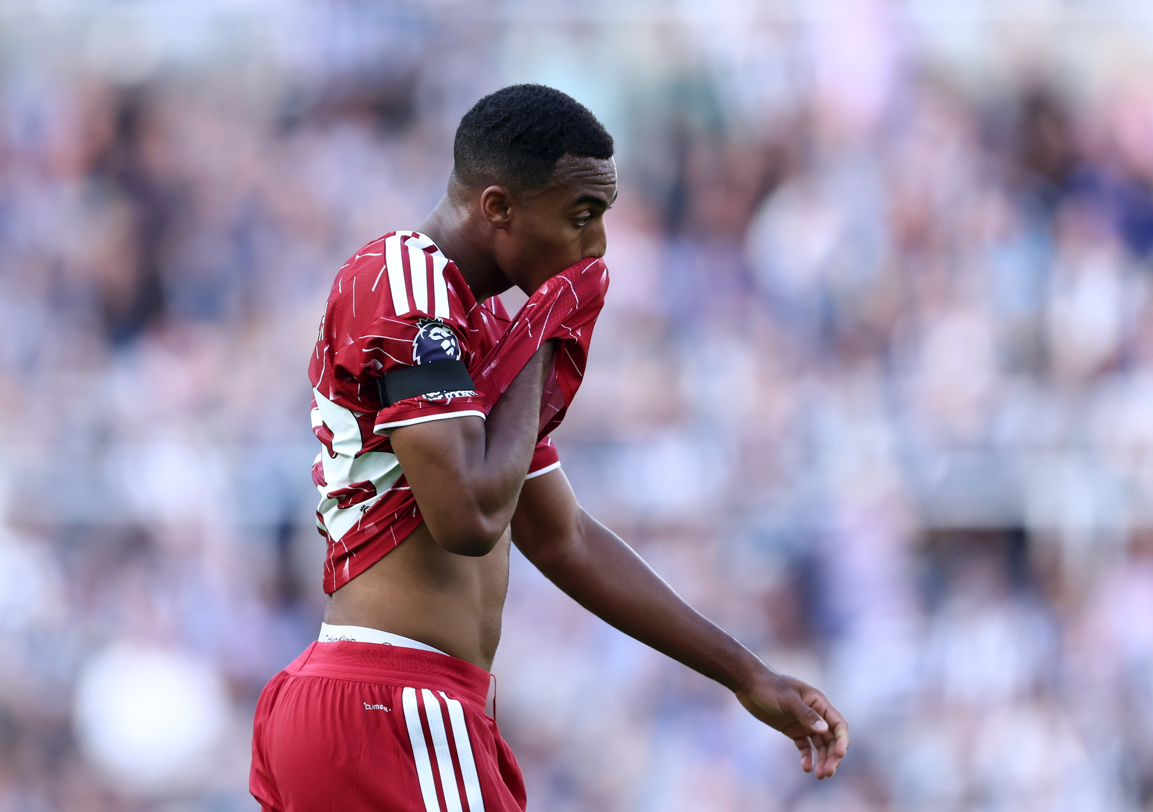Ryan Gravenberch wipes his face with his Liverpool shirt.