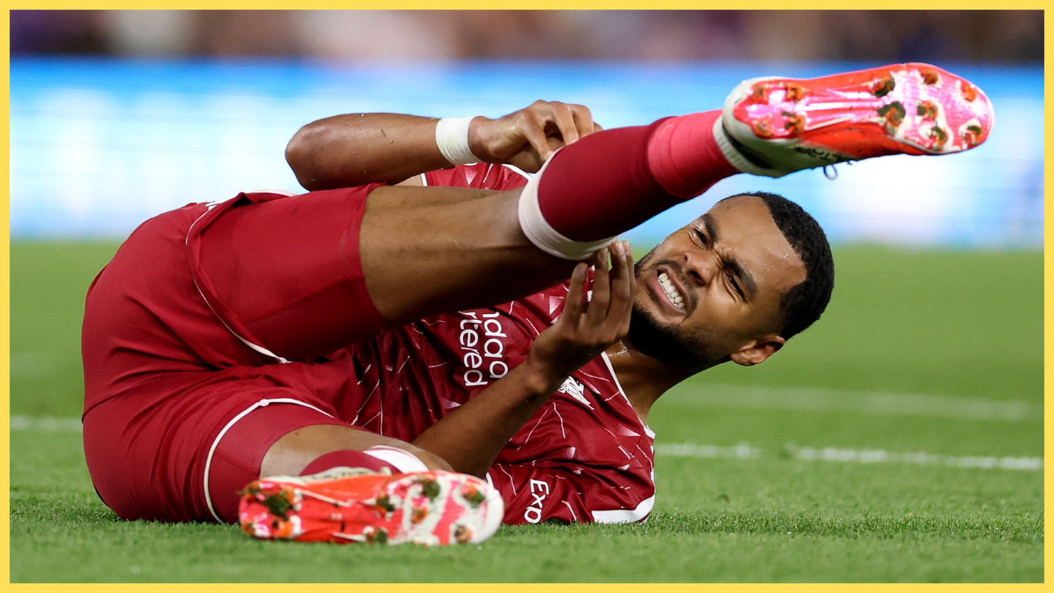 Liverpool winger Cody Gakpo lies on the floor holding his leg in pain.
