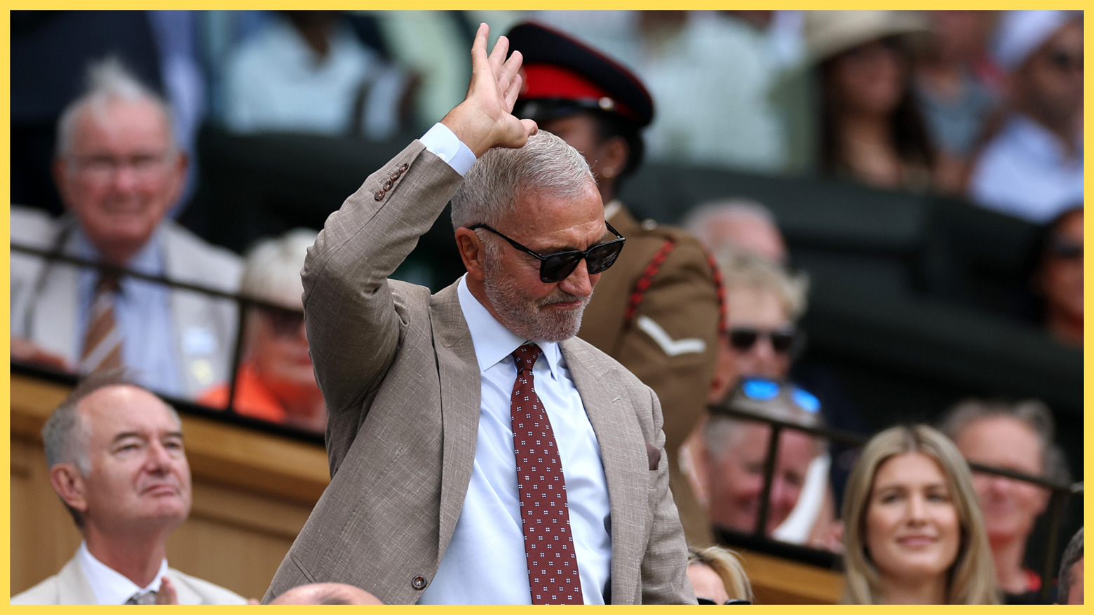 Liverpool legend Graeme Souness stands up and holds up his arm in acknowledgement of the crowd.