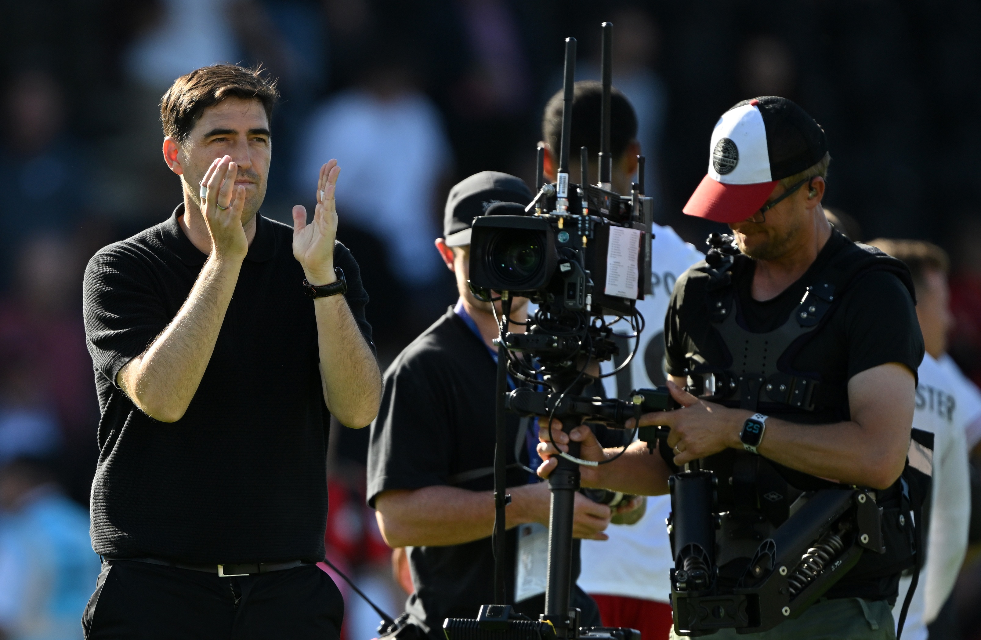 Liverpool manager Andoni Iraola claps his hands next to a camera rig.