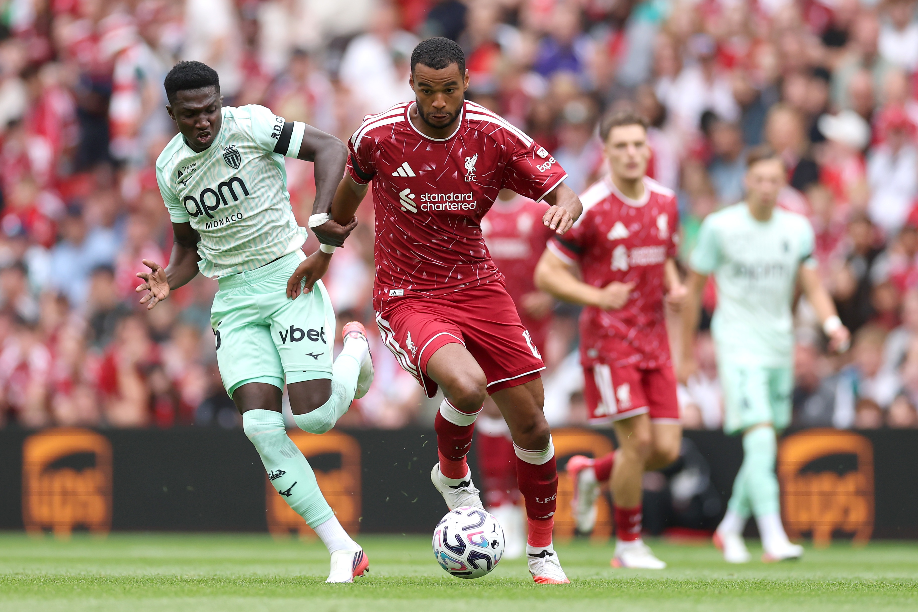 Lamine Camara competes with Cody Gakpo for the ball during Liverpool vs Monaco.