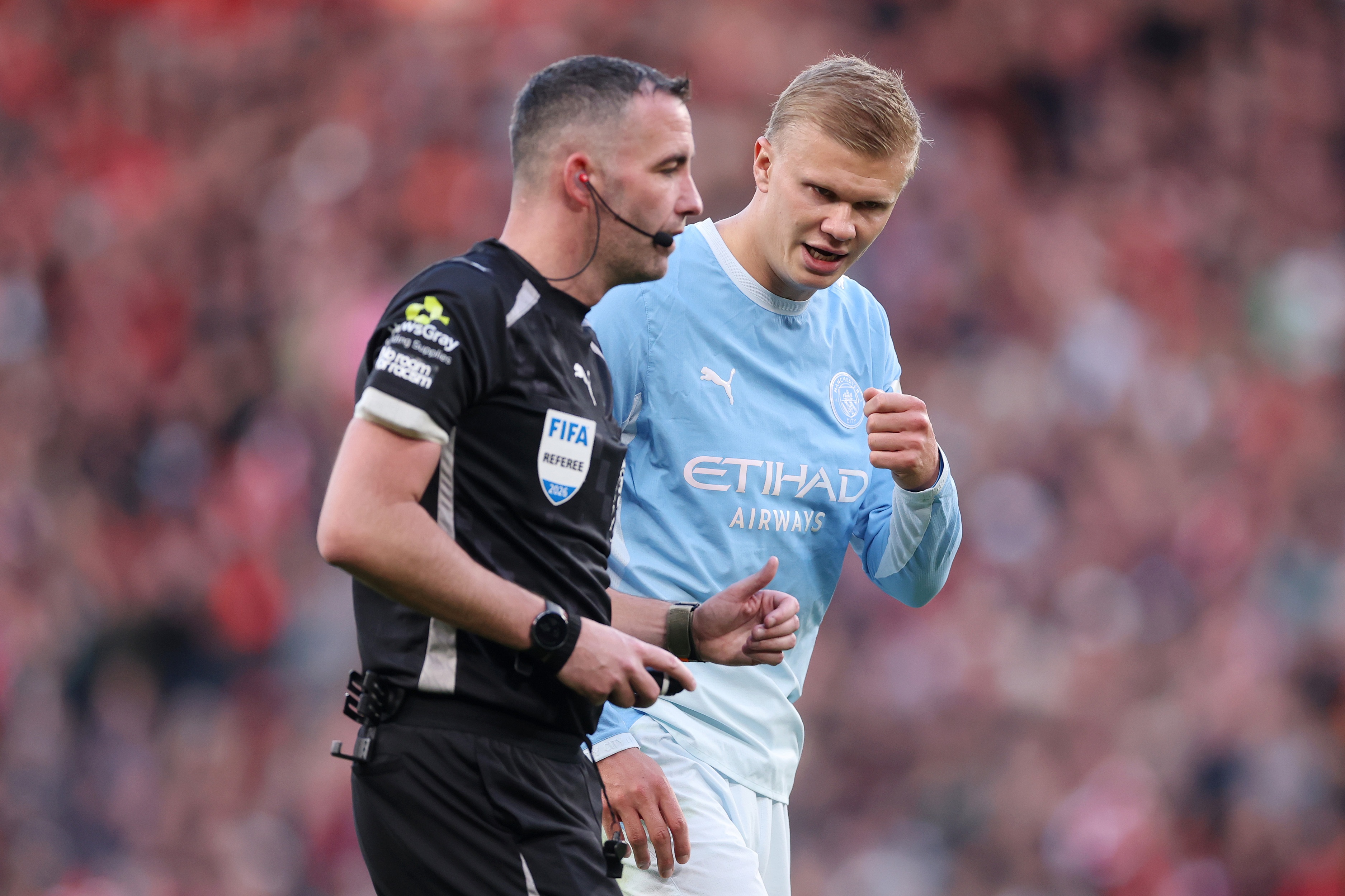 Man City striker Erling Haaland speaks to referee Chris Kavanagh.