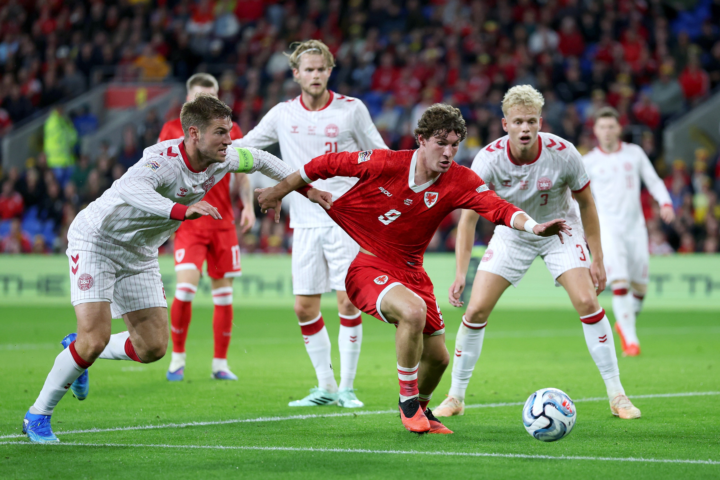 Lewis Koumas dribbles on the ball while under pressure during Wales game.
