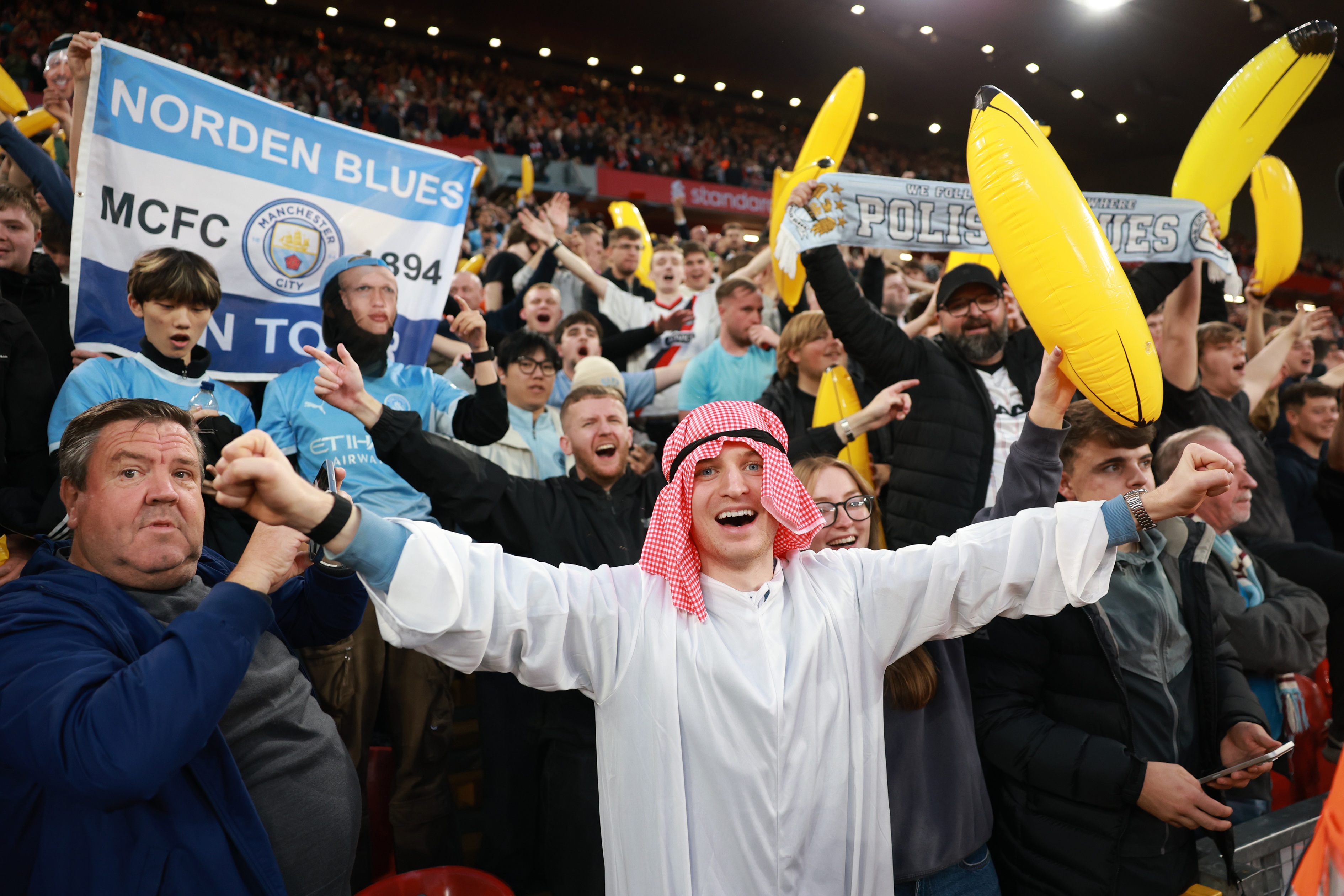 Manchester City fans celebrate in the stands at Anfield.