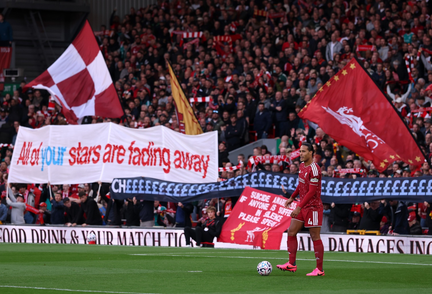 Virgil van Dijk controls the ball amid a backdrop of banners in the Kop at Anfield